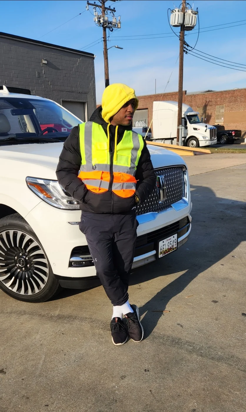 David Couser in a hi vis vest beside a white Lincoln Navigator in the lot